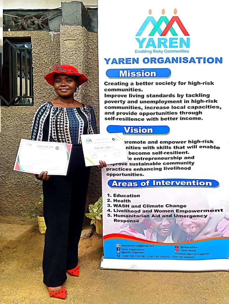 A YAREN graduate in a red hat holding two certificates beside the YAREN mission banner