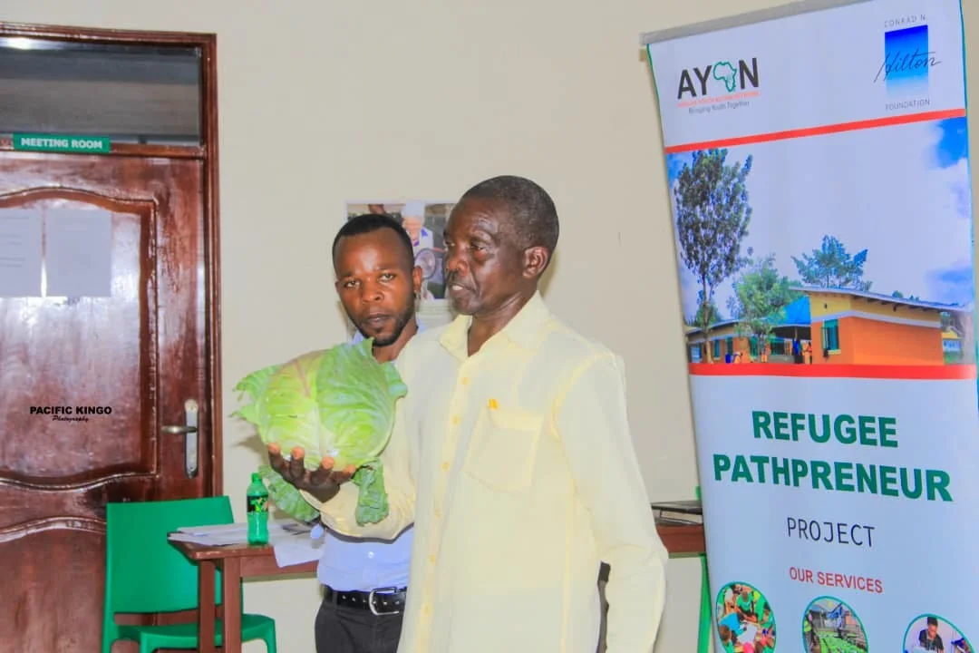 Mr Benone holding a cabbage as he presents his success story to the new cohort