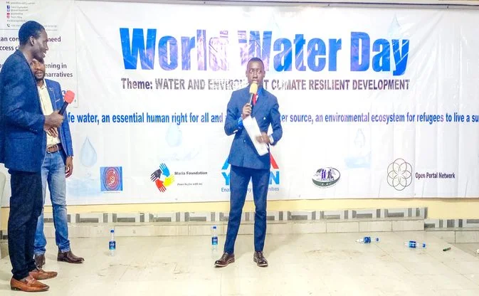 A speaker addressing the dialogue in front of the World Water Day banner