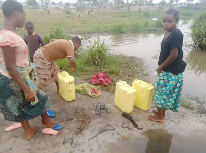 People collecting water at an open source in Nakivale
